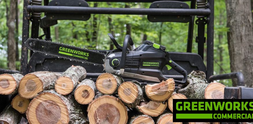 Greenworks Commercial Chainsaw sitting on top a pile of cut up firewood
